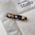 Macro shot of tortoise shell hair clip with white floral patterns and sparkling rhinestones - Amber