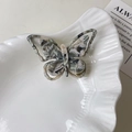 Detail der Schmetterlings-Haarklammer aus Acetat mit Marmormuster und hohlem Flügeldesign - Beigegrau