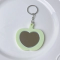 Detail of light green apple-shaped key ring with a heart-shaped mirror on a ceramic plate - Gold Keychain / Green