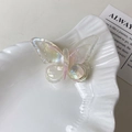 Makro-Detail einer schimmernden, irisierenden Schmetterling-Haarklammer auf weißem Teller - Perlweiß