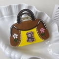 Macro detail of brown and yellow handbag shaped hair claw with pink bear and rhinestone flowers - Brown Bag Style