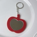 Red apple-shaped keychain accessory with a heart-shaped mirror on a ceramic plate - Gold Keychain / Red Marble