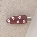 Detailed view of pink resin hair clip featuring 3D white daisy flowers and silver metal grip - Brown