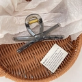 Detailed top view of a translucent charcoal grey bow hair claw clip in a woven basket - Large / Transparent Black