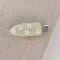 Detailed close-up of yellow resin hair clip with white daisies on grey fabric - Off-white