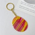 Detailed close-up of mini marble texture comb keychain with golden metal ring and chain - Gold Ring - Textured Red & Yellow