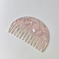 Macro shot of wide-tooth acetate hair comb with elegant pink marble texture and smooth teeth - Pink