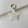 Macro shot of white glitter star keychain with smiley face and silver metal ring clasp - Glitter White