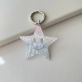 Close-up of glittery acrylic star keychain with a hollow smiley face on leather background - Glitter Blue White