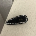 Dettaglio di un fermaglio francese nero con strass colorati e scritte dorate su tessuto - Nero