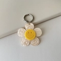 Dettaglio del portachiavi a girasole in acrilico con petali glitterati e un viso sorridente - Beige