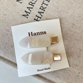 Dettaglio di fermagli per capelli bianco perla con scritte oro su sfondo di lino - Bianco Perlato / Argento Bianco