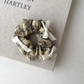 Close-up of yellow checkered scrunchie with white bows on minimalist book background - Plaid Bow Style