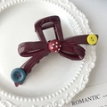 Dettaglio di un fermaglio per capelli rosso scuro vintage con fiocco e bottoni - Stile Rotondo / Rosso