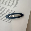 Detailed close-up of a blue oval acetate hair clip on a vintage book page backdrop - Dark Blue