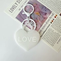 Close-up of matte white heart-shaped keychain featuring 3D embossed LOVE text detail - White