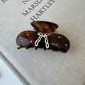 Tortoiseshell hair claw clip with white bow pattern and rhinestones on a beige book - Amber Tortoiseshell Claw Clip