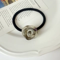 Macro detail of amber resin rose charm on high-elasticity black spiral hair tie - Iridescent Gray