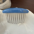 Detail eines blauen Haarkamms aus Acetat mit goldenem Logo und silbernen Metallzinken - Blau