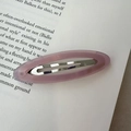 Pink translucent acetate oval snap hair clip with AM BEAR text on an open book - Pink