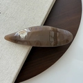 Détail de la pince à cheveux en résine ambre foncé avec texture écaille sur disque en bois - Marron