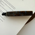 Close-up of tortoise shell pattern acetate hair clip on vintage book page with soft lighting - Blue Coffee