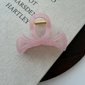 Detailed close-up of a pink translucent ribbon hair claw clip on a texture book - Pink