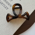 Close-up of a tortoiseshell bow hair claw clip on a canvas book and wooden tray - Glossy French Amber