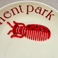 Detail view of a ladybug-shaped red cellulose acetate hair comb on a ceramic plate - Approx. 9.8cm*3.4cm