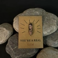 Macro detail van Rhodoniet kristalpunt op een YOU'RE A REAL GEM kraft cadeaukaart - Rhodoniet