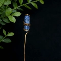 Vista macro de un pasador de cristal de sodalita azul envuelto en hilo de oro artesanal - Sodalita azul