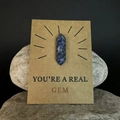 Macro-opname van blauwe kristallen kolom op kraft cadeaukaart met tekst You are a Real Gem - Blauwe Puntsteen