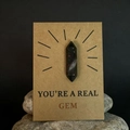 Gepolijste zwarte kristallen steen met rode vlekken op een 'You're a Real Gem' cadeaukaart - Afrikaanse Bloedsteen