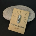 Zeshoekige kristallen pilaar op een YOU'RE A REAL GEM-cadeaukaart op natuurlijke kiezelachtergrond - Natuursteen