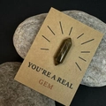 Macro-opname van natuurlijke donkere kristal op een kraft cadeaubon met You're a Real Gem - Tijgeroog