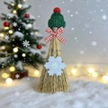 Detail van decoratieve kerstbezem met rode gebreide muts op kunstmatige sneeuw - Groene Muts Sneeuwvlok