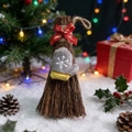 Dettaglio di una scopa di Natale con nastro 'Merry Christmas' e guanto di peluche - Fiocco e Guanto
