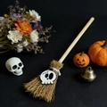 Macro shot of a mini witch broom with a skull pendant on a black Halloween background - Ghost White