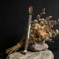 Dettaglio di una penna in legno rustico con cristallo arcobaleno su pietre naturali - Rosa Giallo Verde