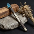 Close-up of wooden magic wand pen with blue raw crystal top on natural stone - Blue