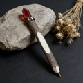 Detailed close-up of a rustic wooden pen with a dark red crystal and vintage metal accents - Burgundy