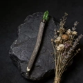Detailed close-up of a rustic wooden magic wand pen with a raw green crystal top - Green