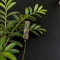 Dettaglio di un paletto in resina fatto a mano con fiori secchi e filo dorato per piante - Unakite