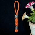 Detail of orange paracord keychain featuring a silver tribal mask bead and viking runes - Orange