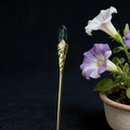 Macro detail of a gold alloy vintage hair pin with a hexagonal green crystal stone - Southern Jade