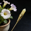 Detail of a gold floral hair pin featuring a yellow hexagonal crystal point - Topaz