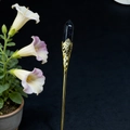 Detail of a vintage golden hair pin featuring a faceted deep blue crystal and filigree - Blue Goldstone
