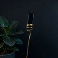Macro detail of natural black crystal stone with golden handcrafted spiral copper wire support - Obsidian