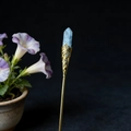 Detailed close-up of a blue crystal hair pin with intricate golden filigree work - White Turquoise