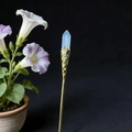 Detail of a gold-tone hair stick with a hexagonal blue crystal and intricate carving - Opal